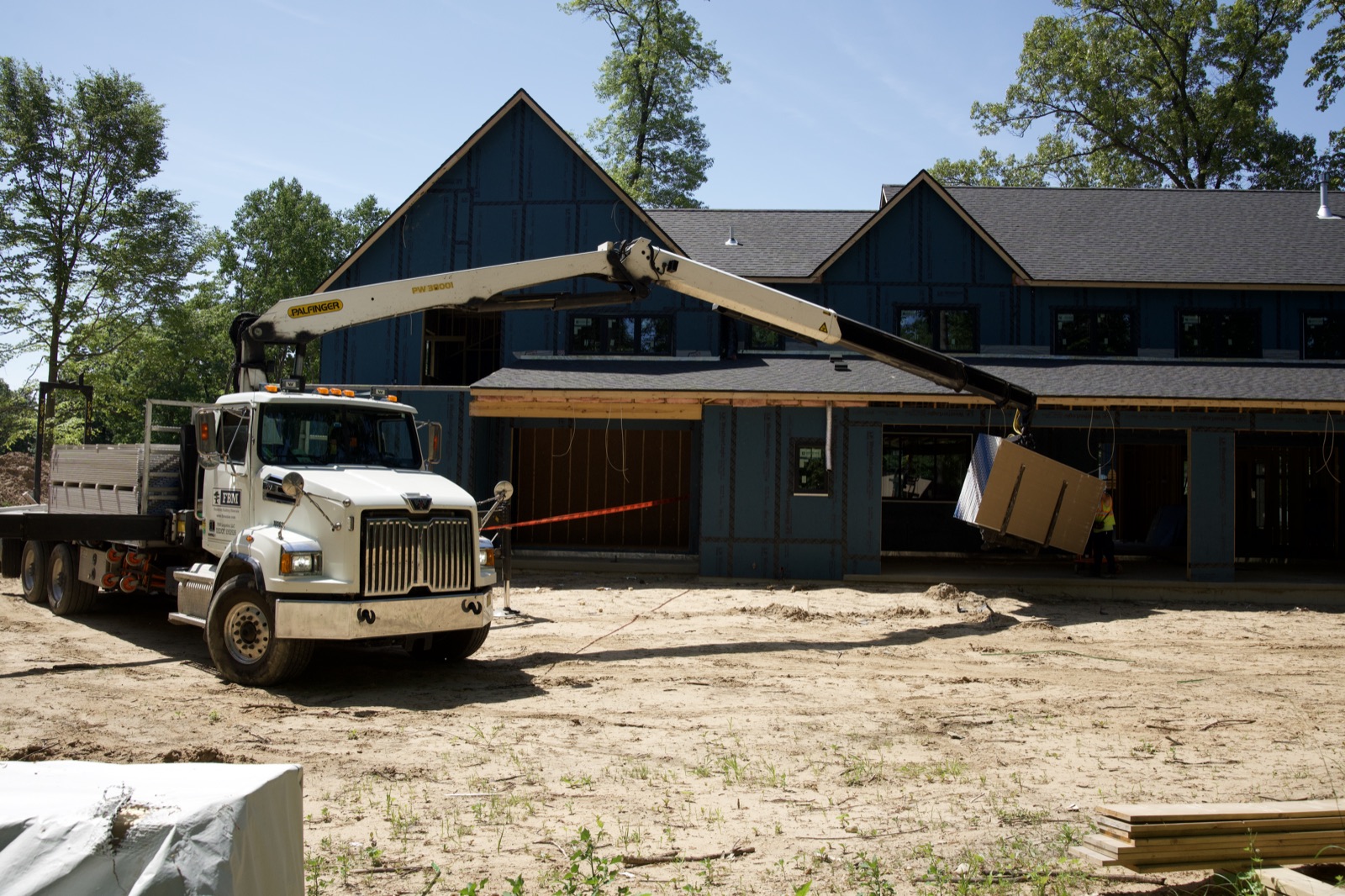 Boom truck delivering drywall to a new construction home