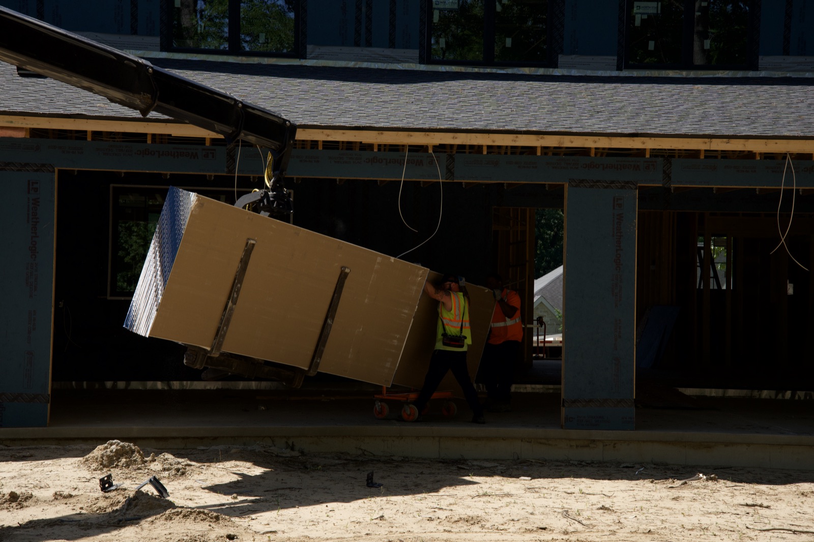 Drywall bundle craned under the porch roof