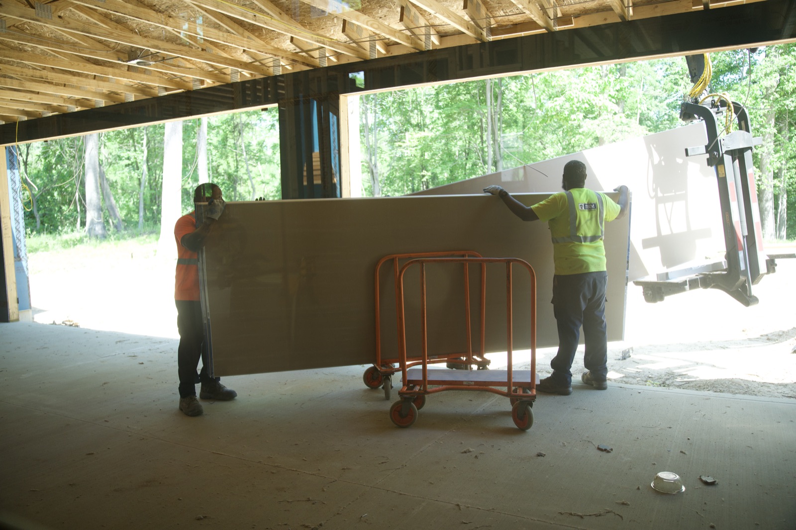 Two workers loading drywall onto a cart
