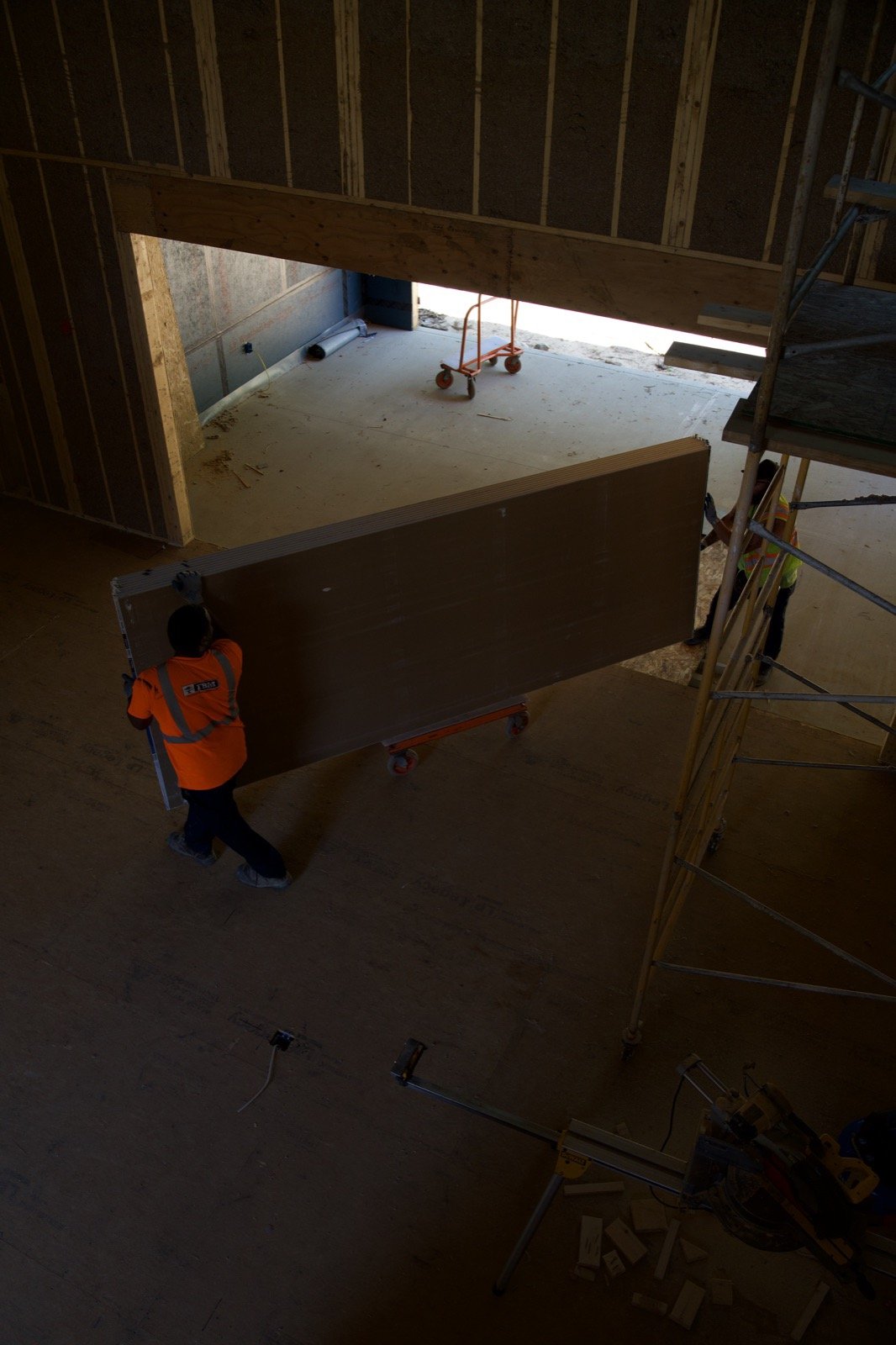 Carrying a sheet of drywall through the framing