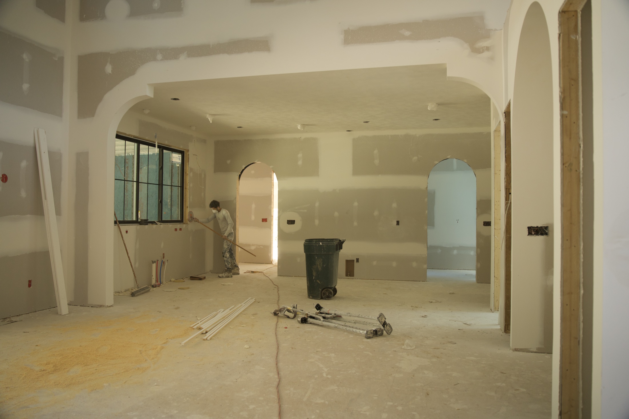 Worker finishing drywall in an open living area